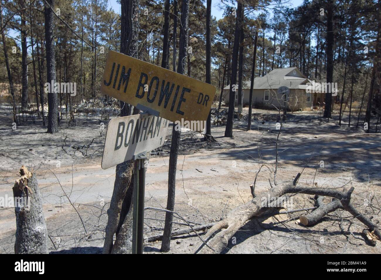 Bastrop County Texas USA, September 9 2011: Scorched street signs show how close fire came to an unburned home in the aftermath of wildfires that raced through the piney woods in Bastrop County 30 miles east of Austin. The fires destroyed 1,400 houses and scorched over 38,000 acres while it was out of control for five days. ©Bob Daemmrich Stock Photo