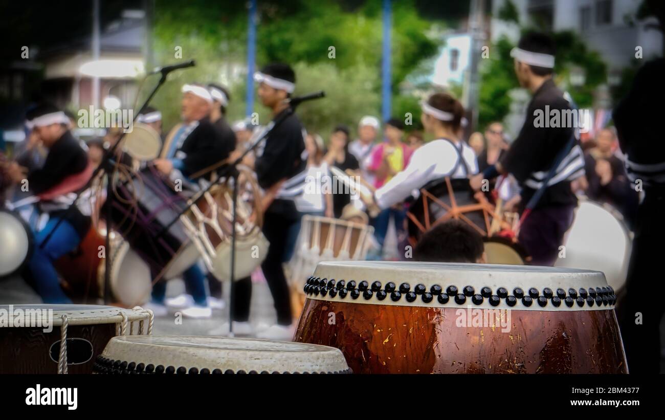 Taiko drums sit on stage with musicians performing in the background at