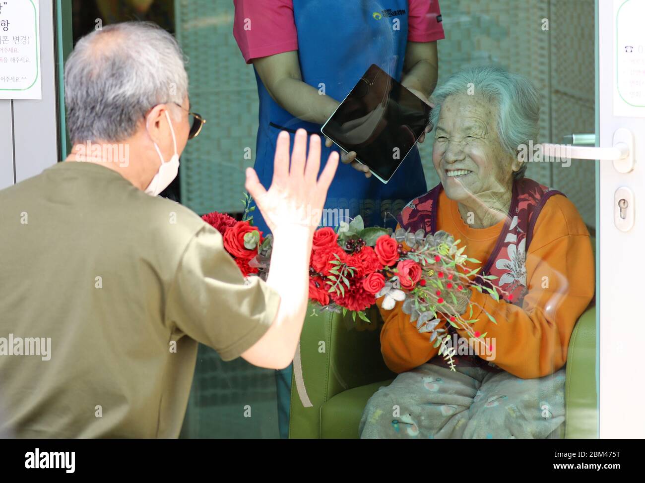 07th May, 2020. Ahead of Parents' Day A son waves to his mother from behind a glass panel at a senior care facility in the central city of Daejeon on May 7, 2020, as he meets her without person-to-person contact one day ahead of Parents' Day amid the spread of the new coronavirus. Credit: Yonhap/Newcom/Alamy Live News Stock Photo