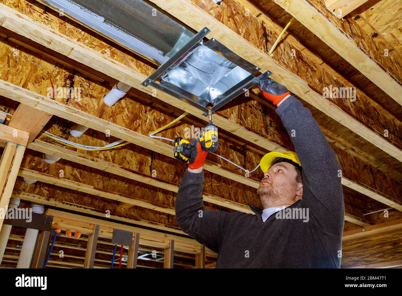 Male technician mounted air heating and cooling system on ceiling steel