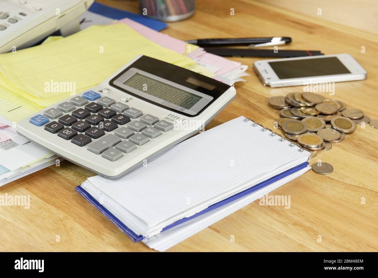 the calculator with coin on wood table at office, concept of calculating expenses, incomes and expenses. Stock Photo