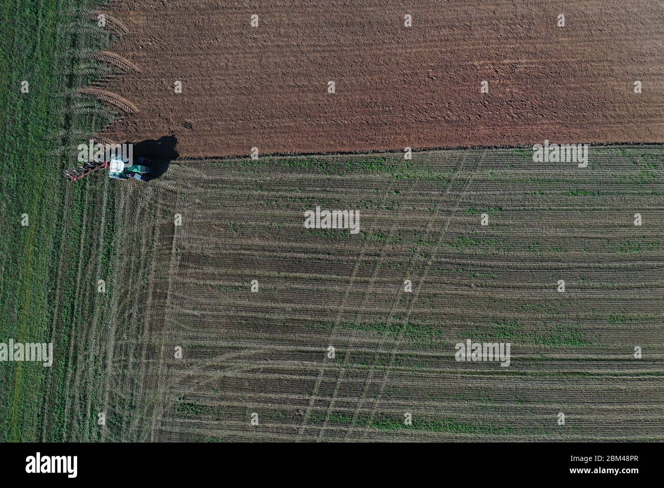 Tractor ploughing farm field in summer end, aerial view Stock Photo