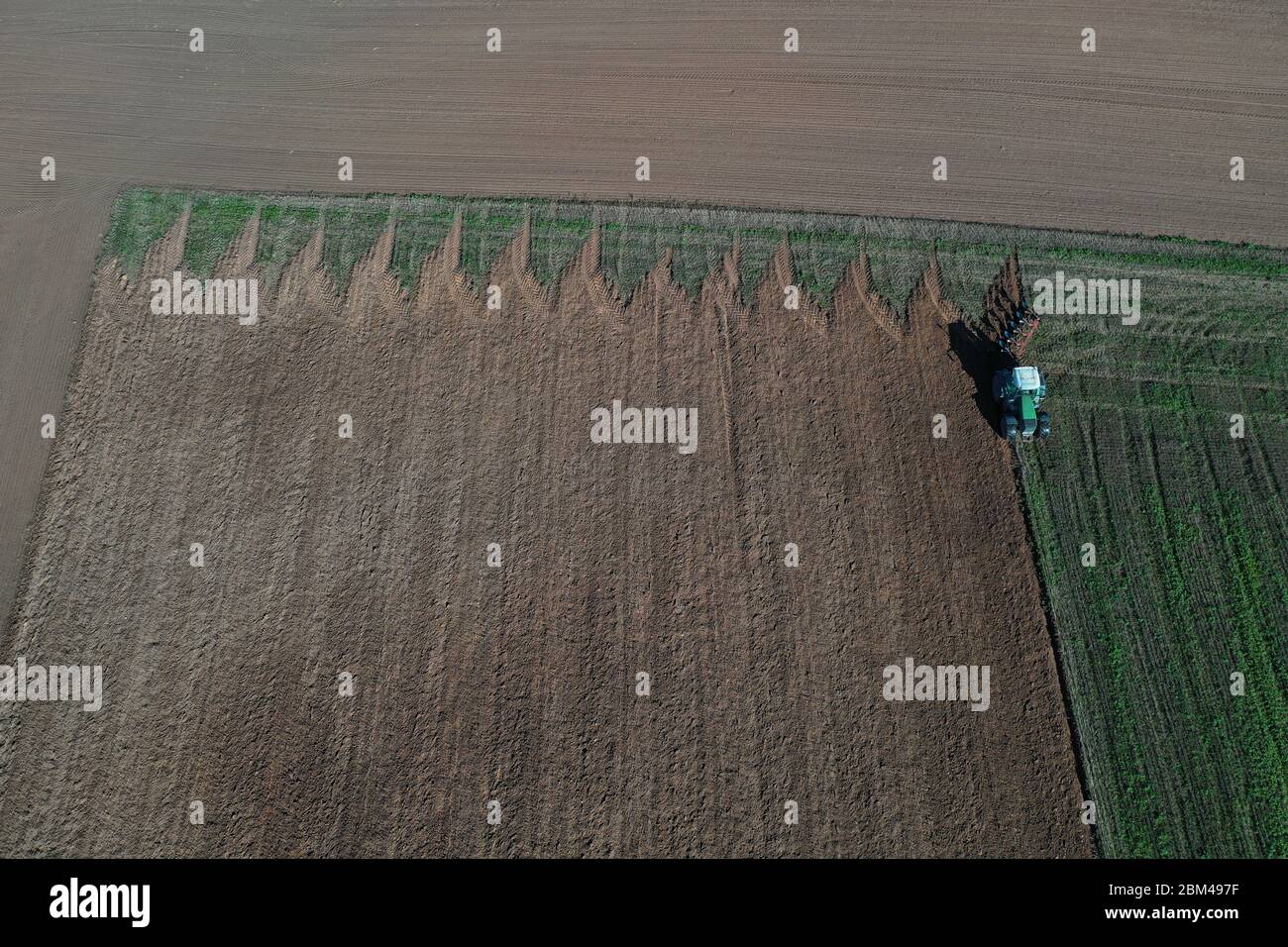 Tractor ploughing farmland field in summer end, aerial view Stock Photo