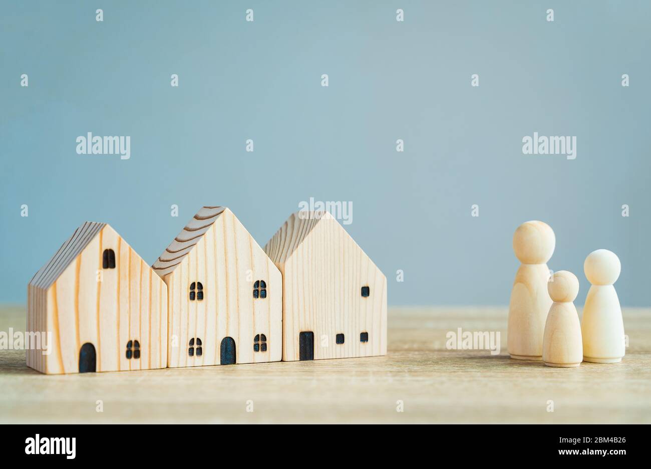 Money savings concepts. Wooden house models with family wooden dolls in meaning about saving money to buy a house, refinancing, investment or financia Stock Photo