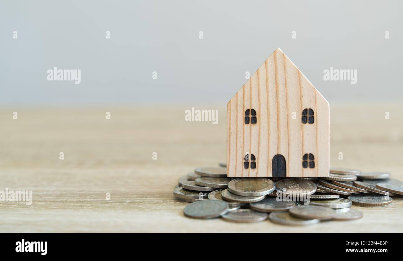Money savings concepts. Wooden house models with coins in meaning about saving money to buy a house, refinancing, investment or financial on wooden ta Stock Photo