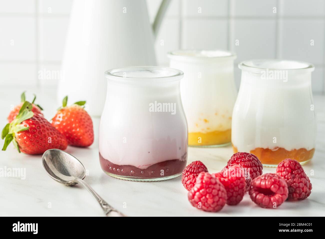 https://c8.alamy.com/comp/2BM4C01/white-fruity-yogurt-in-jar-and-raspberries-on-white-table-2BM4C01.jpg