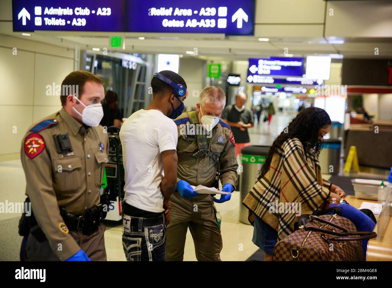 Dallas, United States. 06th May, 2020. Police officers wear face masks as a preventive measure while verifying the identification of passengers arriving at an American Airlines flight in Texas during quarantine amid Coronavirus.Passengers were asked if they were staying in Texas and those who said they were staying in Texas were told to self-quarantine for 14 days under an order from Texas Governor Greg Abbott. Travels not complying with the order are subject to a 1000-dollar fine and either 180 days in jail, or both. Credit: SOPA Images Limited/Alamy Live News Stock Photo