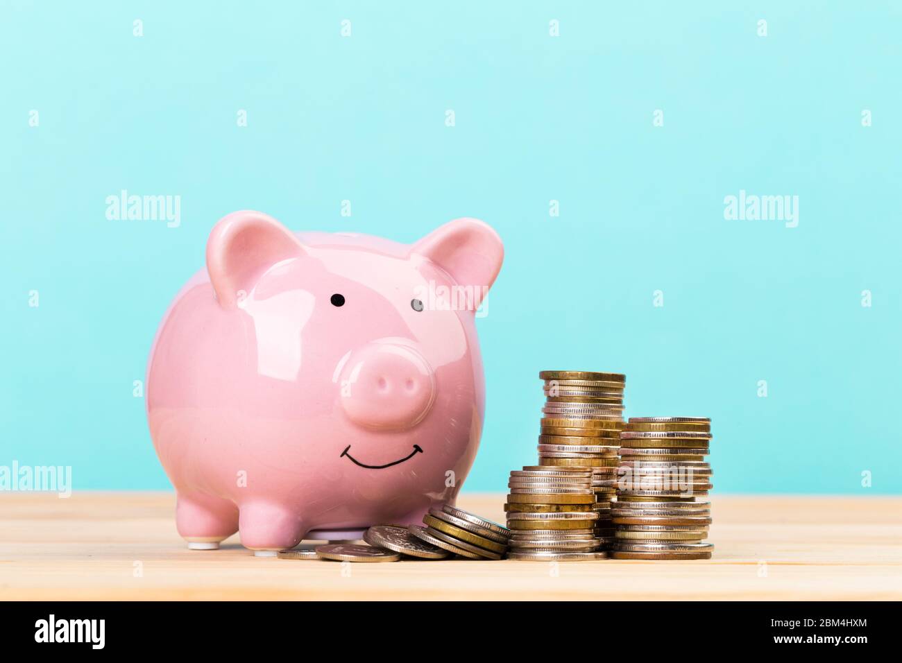 Pink piggy bank on wooden table and blue background. The concept of ...