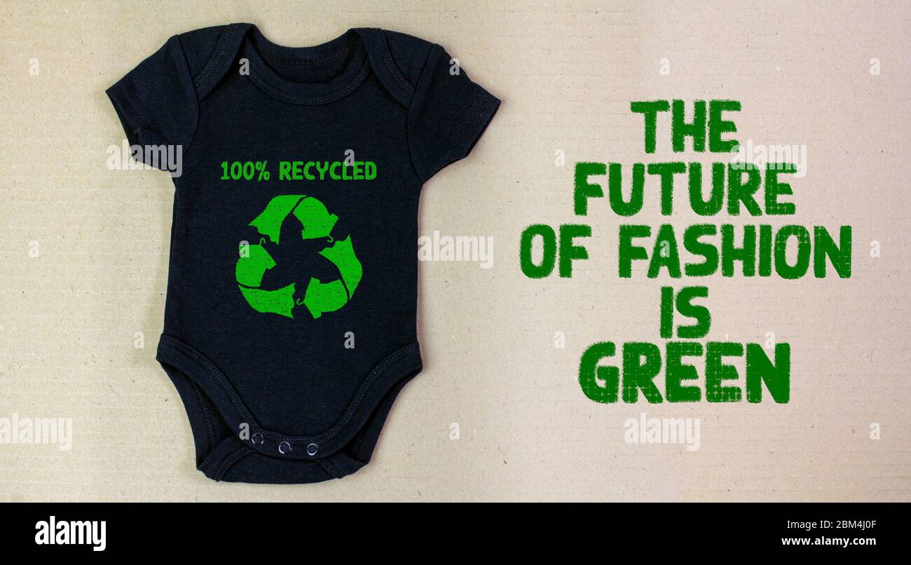 Recycled fabric baby grow with the future is green text on recycled cardboard background. Zero waste and sustainable fashion concept Stock Photo
