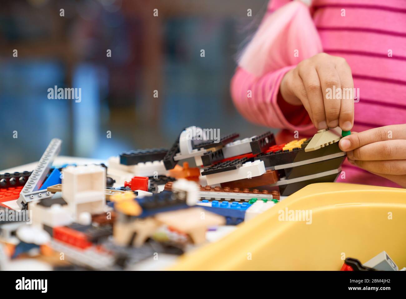 Front view of building kit for kids creating toys, having positive emotions and joy. Crop of incognito african girl working on project, hands taking colorful parts. Concept of science engineering. Stock Photo