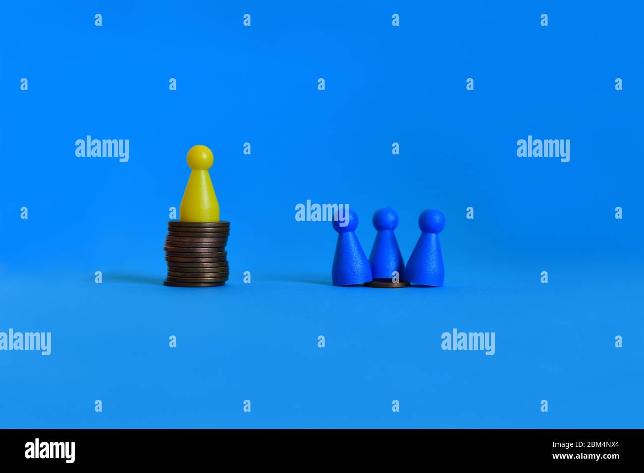 Pawns standing on piles of different sizes of coins. Income and economic inequality concept. Stock Photo