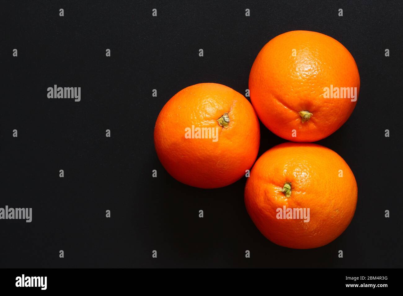 Three healthy oranges together on a dark surface, with copy space Stock Photo