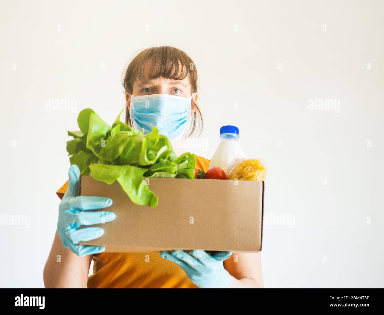 Woman in face mask with food delivery box Stock Photo - Alamy