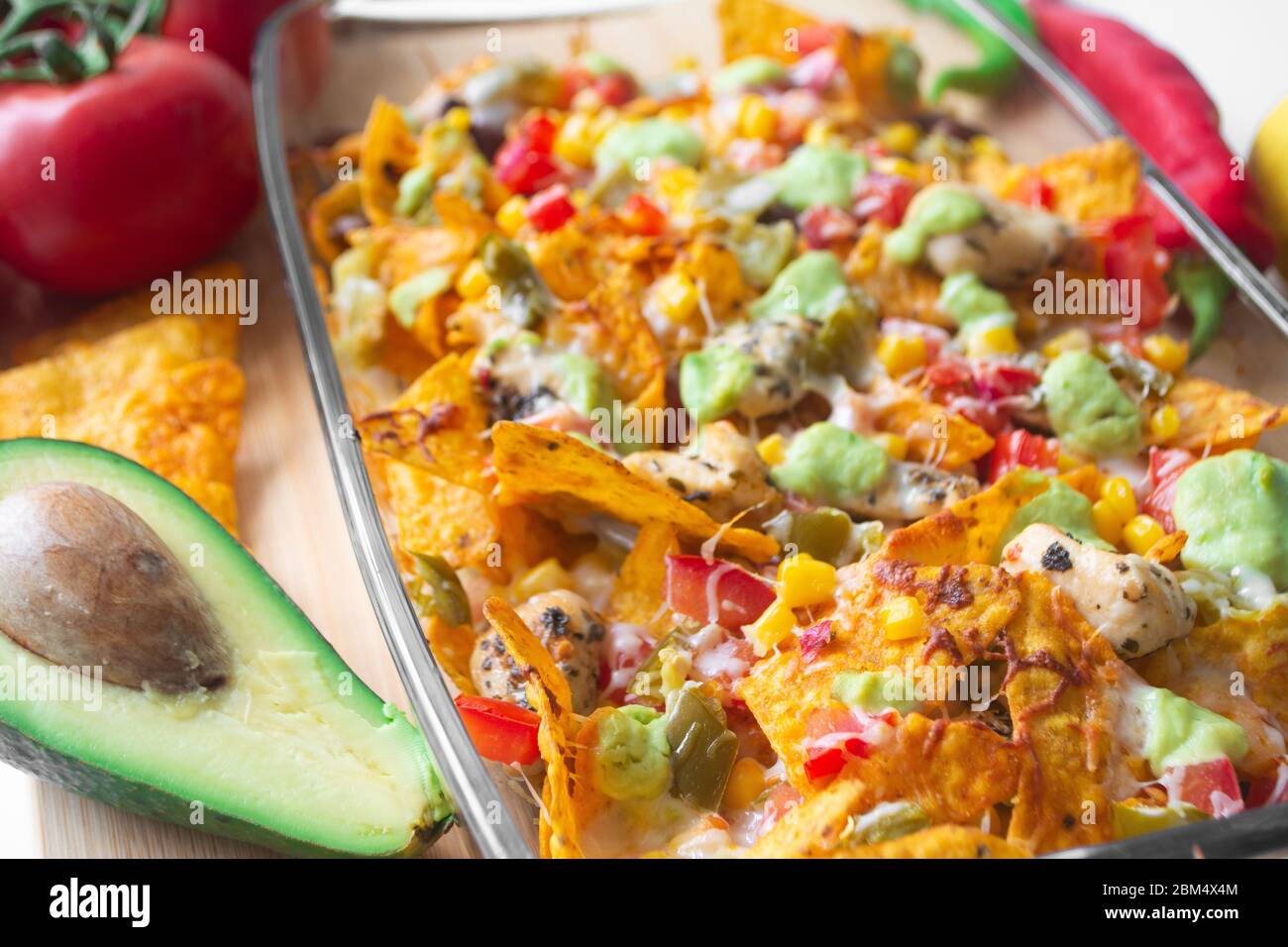 Baked nacho dish in a glass baking pan with corn tortilla chip, pico de