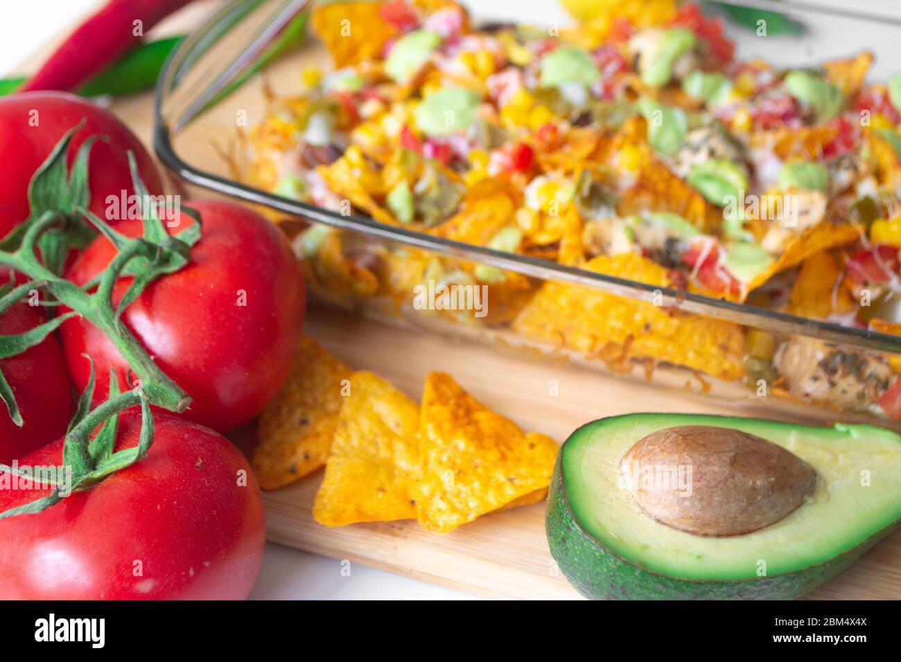 Baked nacho dish in a glass baking pan with corn tortilla chip, pico de