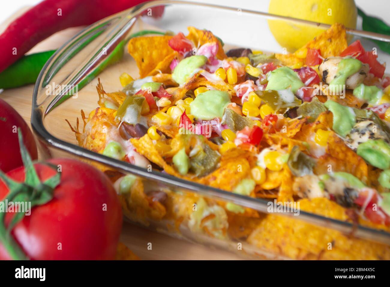 Baked nacho dish in a glass baking pan with corn tortilla chip, pico de