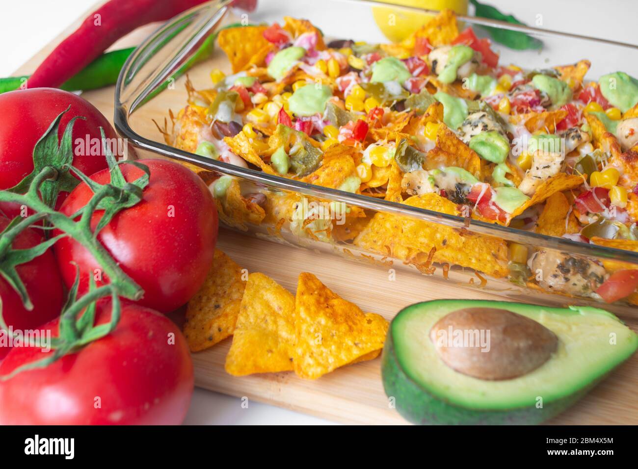 Baked nacho dish in a glass baking pan with corn tortilla chip, pico de