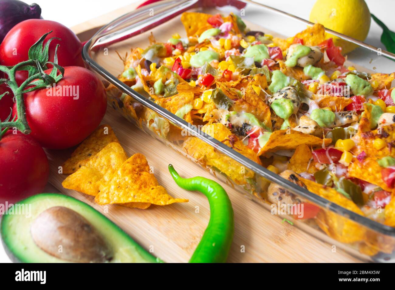 Baked nacho dish in a glass baking pan with corn tortilla chip, pico de