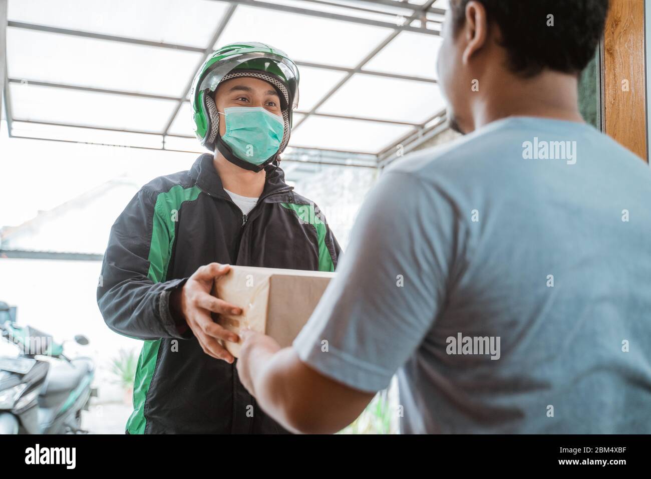 delivery courier wear face masks while delivering package to a man in ...