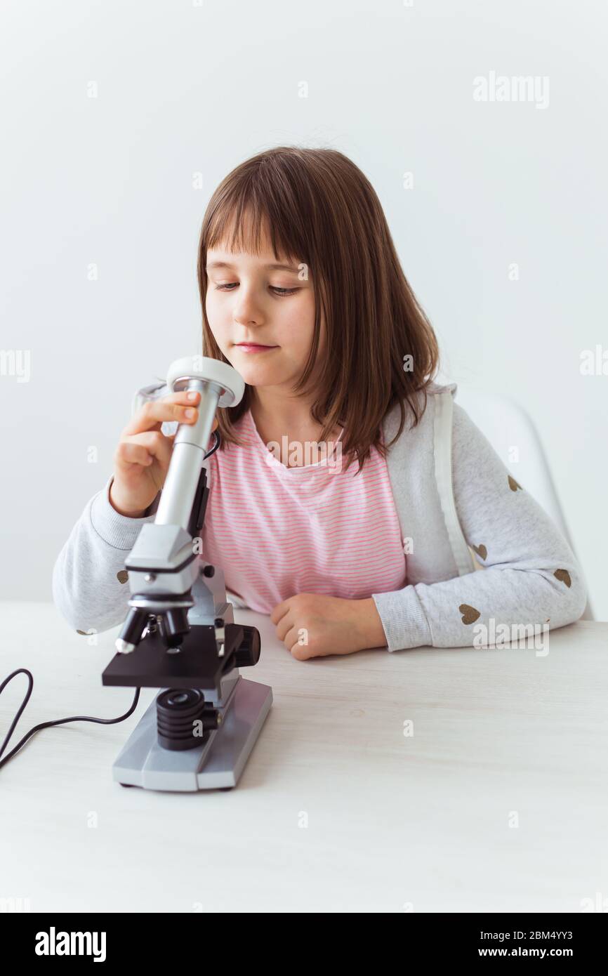 Child girl in science class using digital microscope. Technologies