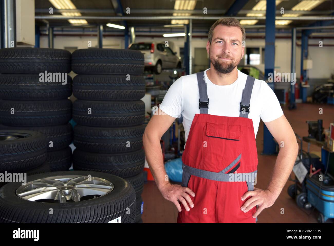 Portrait of successful smiling car mechanic in a on a stack of