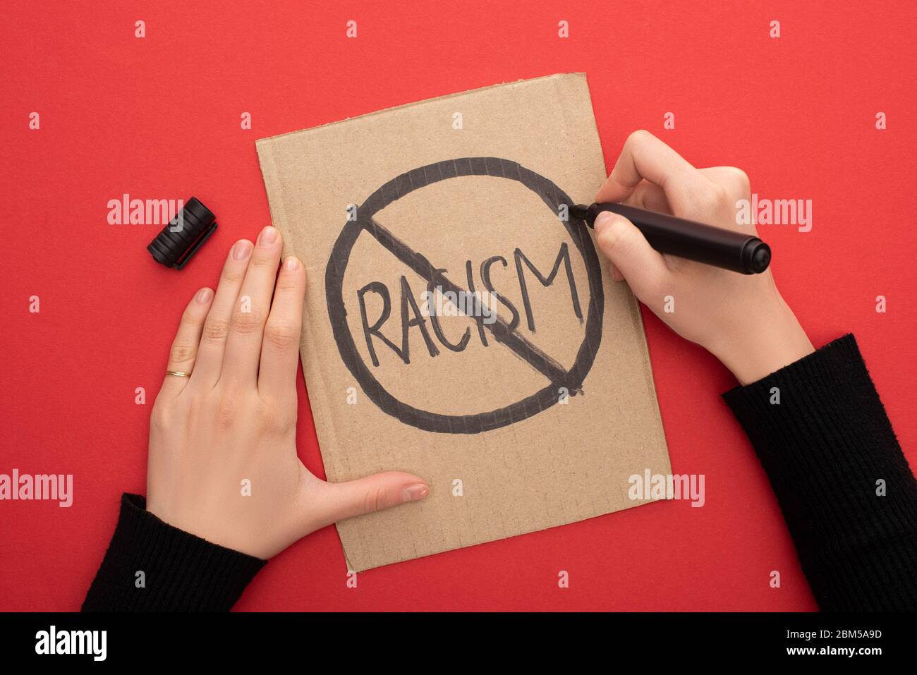 End Racsism Writing cropped view of woman writing stop racism sign with marker on carton ...