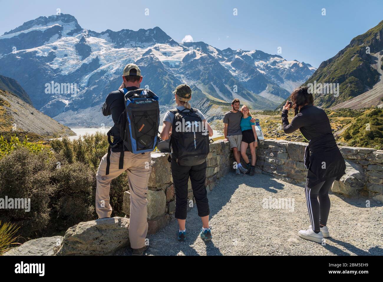 Tourists taking photos on the Hooker Valley Track with a backdrop of Mount Sefton, Aoraki Mount Cook National Park, South Island, New Zealand Stock Photo