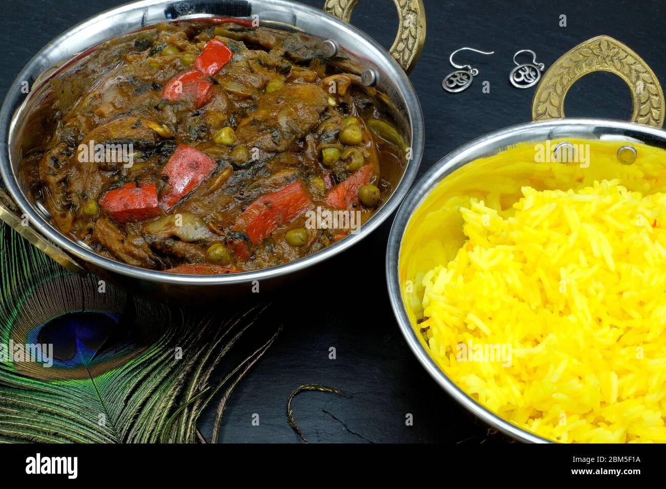 A bowl of mushroom and red pepper curry with accompanying saffron rice Stock Photo
