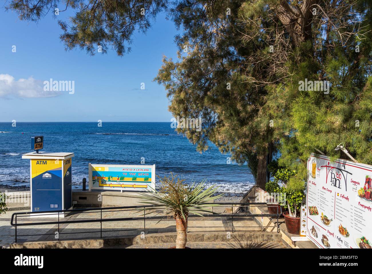 ATM machine and restaurant menu on a path to access Playa Fanabe beach during the Covid 19 State of Emergency in Costa Adeje, Tenerife, Canary Islands Stock Photo