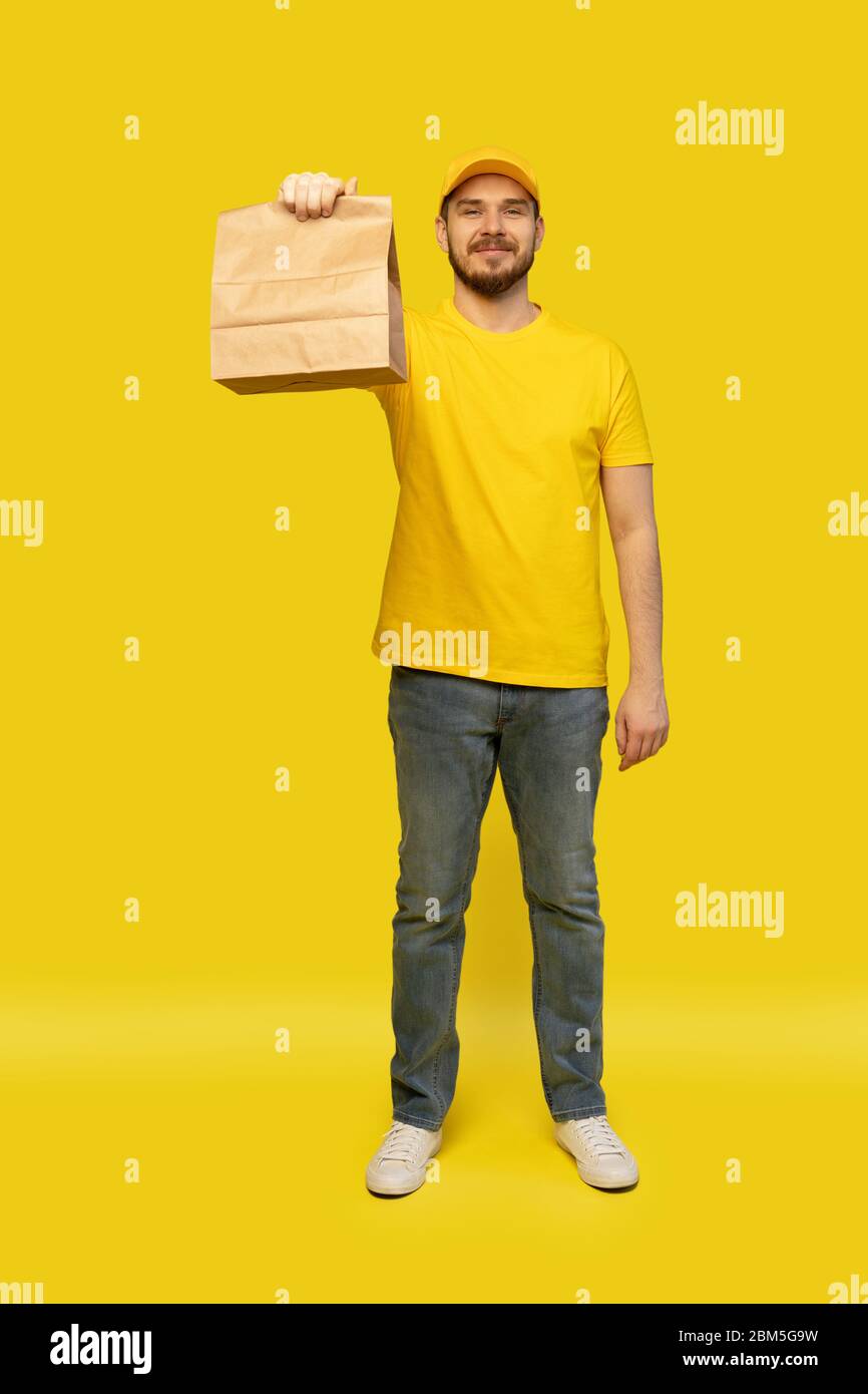 Download Delivery Man Holding Paper Bag With Food On Yellow Background Stock Photo Alamy Yellowimages Mockups