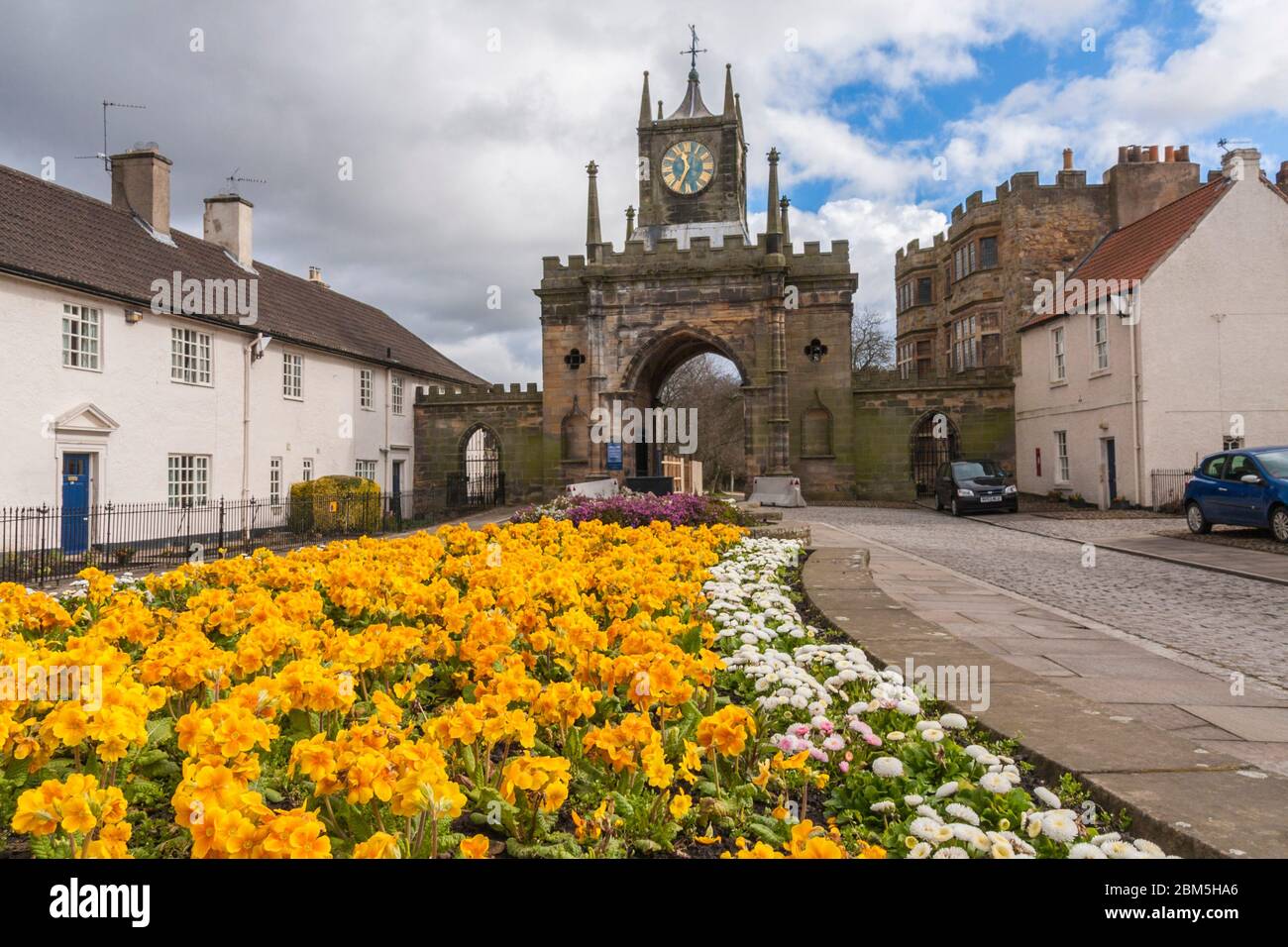 Entrance to Auckland Castle in Bishop Auckland,Co.Durham,England,UK showing the bright yellow flowers and blue moody skies Stock Photo
