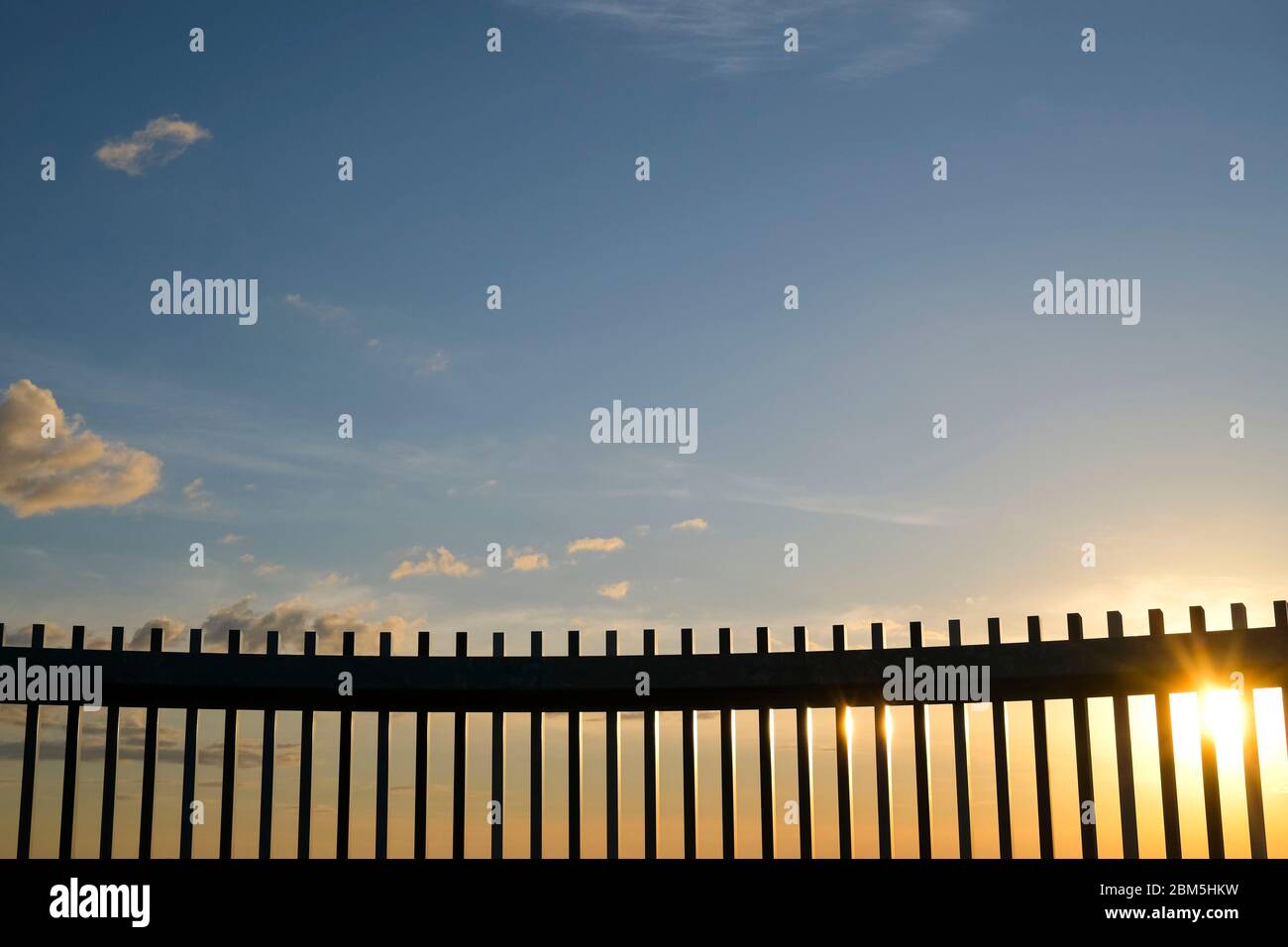 Sun Rising Over Fence Fence against the sky at sunrise Stock Photo - Alamy