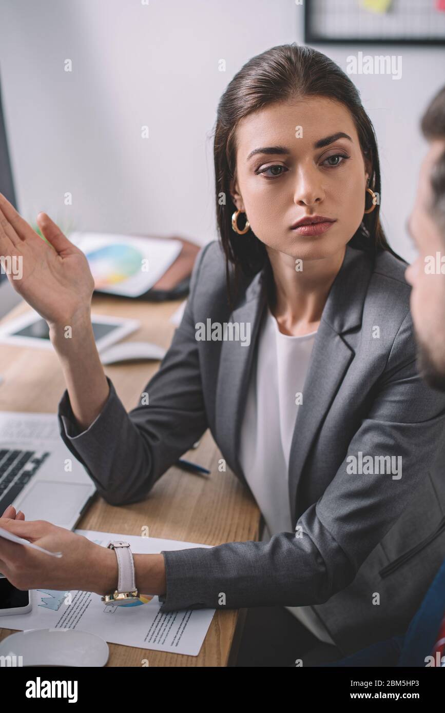 Selective focus of computer systems analyst looking at colleague near ...
