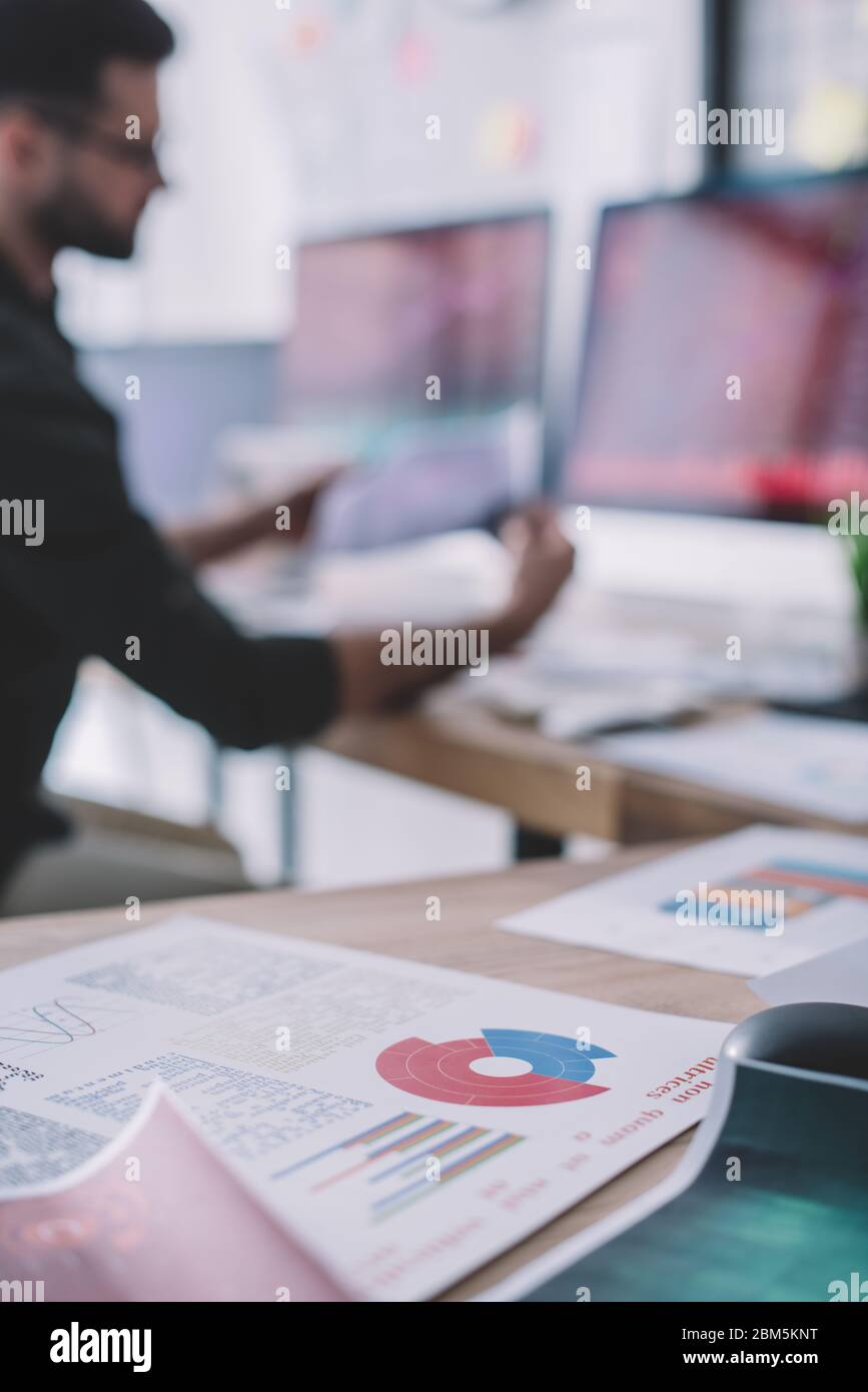 Selective focus of papers with graphs on table and data analyst working ...