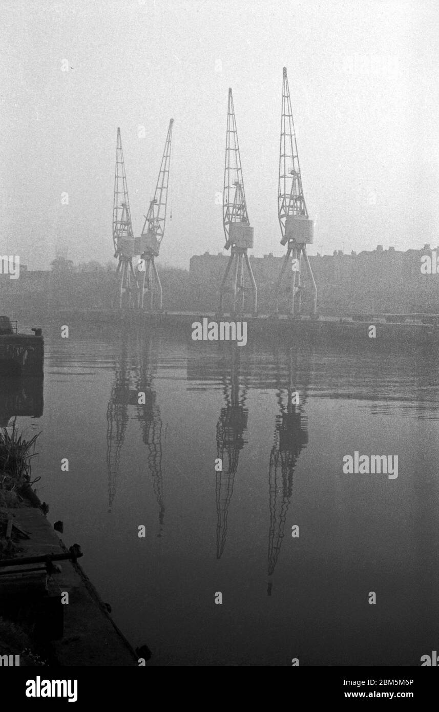 Bristol in the Sixties: A foggy day close to Bristol Cathedral in November 1968.  A view of Bristol Docks looking from the Canons Marsh side near the gas works across the Floating Harbour to an area near Princes Wharf.  The docks remained in action using electric cranes built in Bath through the 60s up until the last regular cargo shipment in 1974. Stock Photo