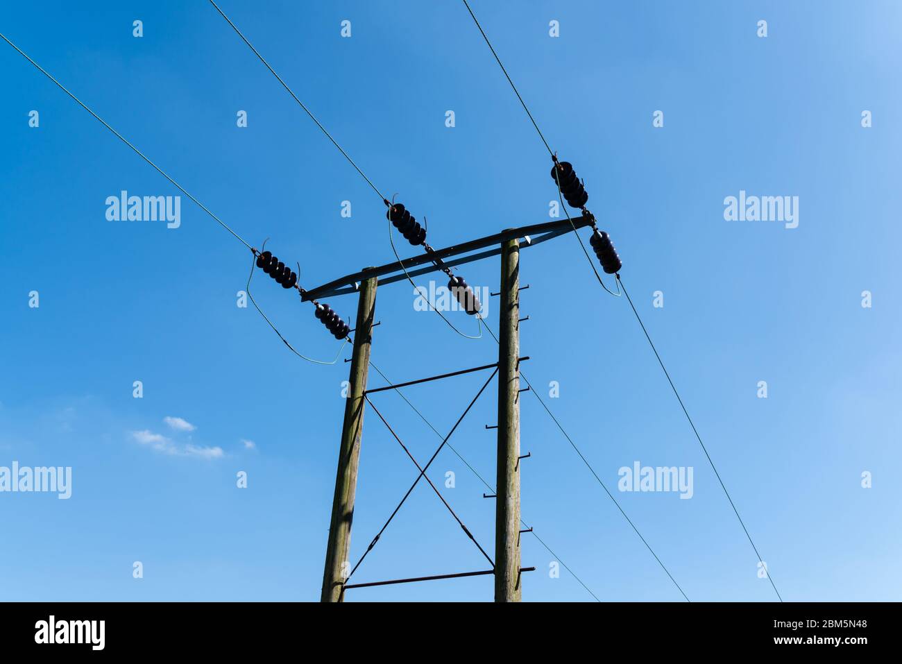 Electric cables and wooden pylon set against a blue sky Stock Photo