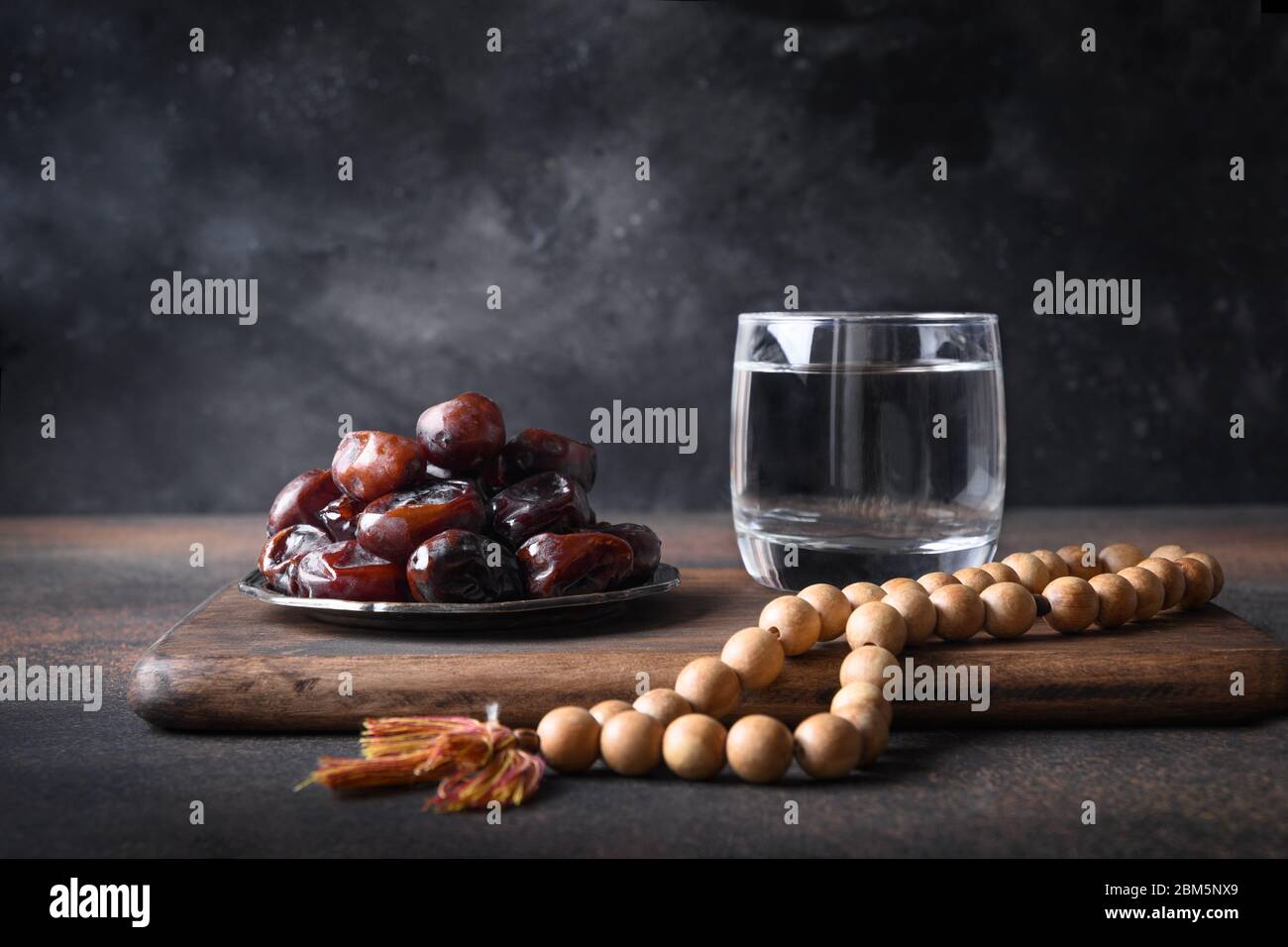 Ramadan. Wooden prayer beads and dates in bowl on brown. Eid Mubarak. Religious tradition. Stock Photo