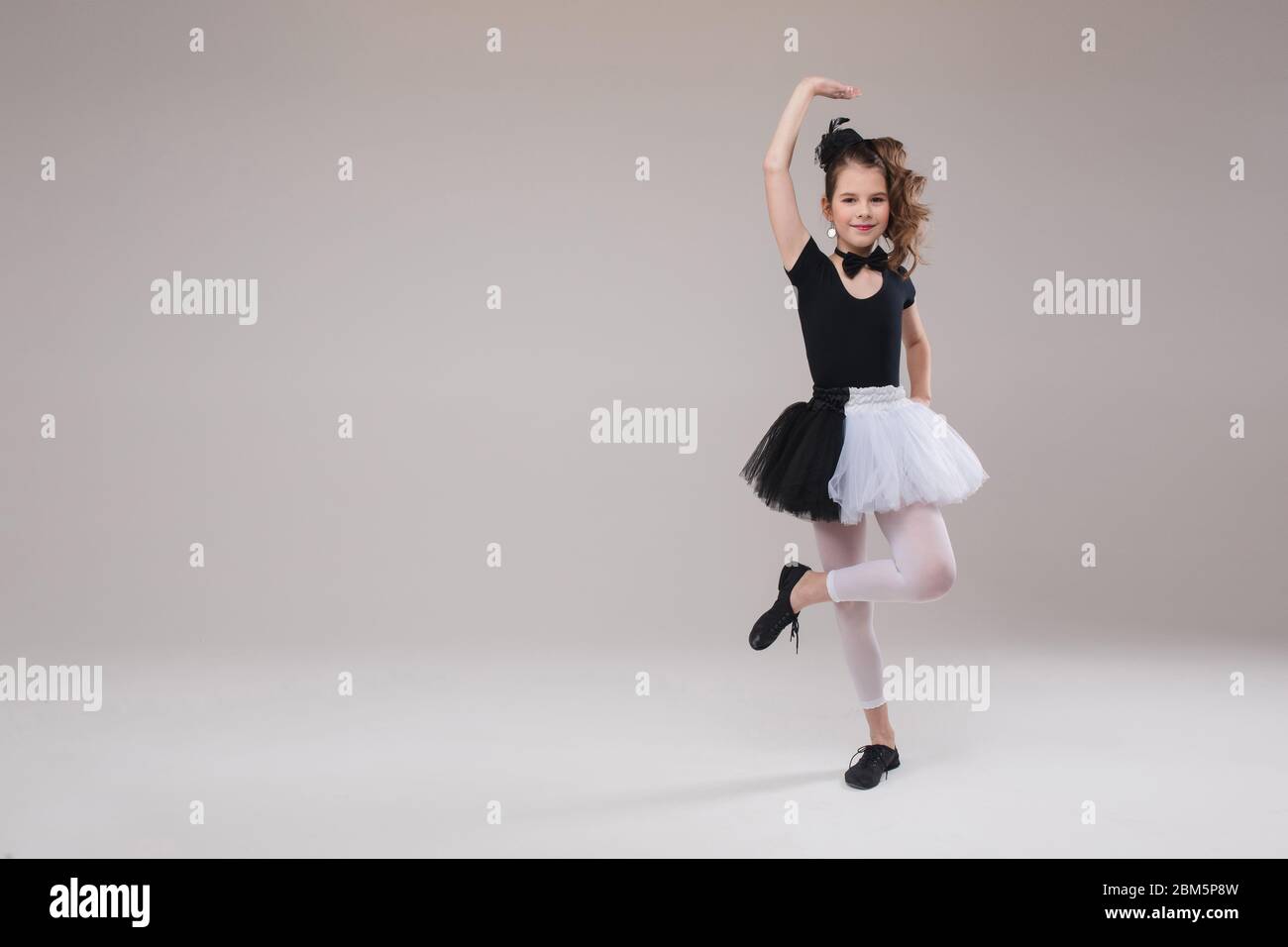 Little baby girl ballerina dancing in black and white clothing smiling having positive emotion