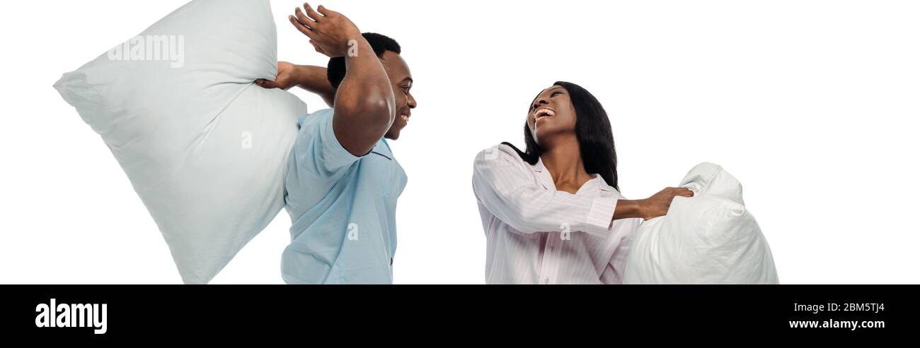 happy african american couple having pillow fight in pajamas isolated on white, panoramic shot Stock Photo