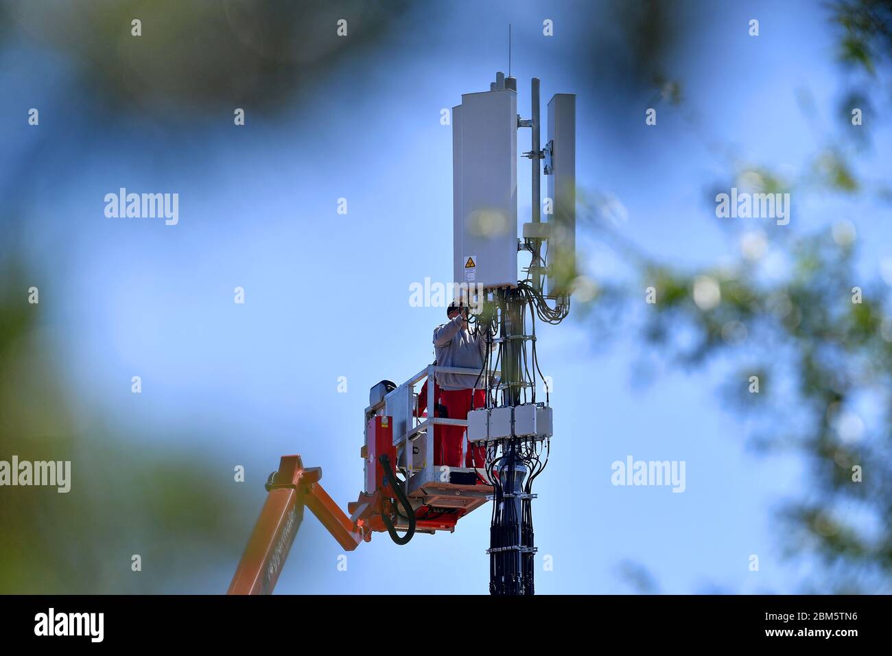 Cell phone mast on a house roof. Workers stand on a lifting platform