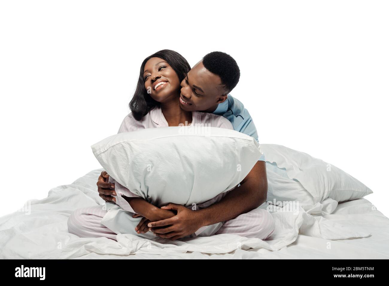 happy african american couple hugging pillow in bed in pajamas isolated ...