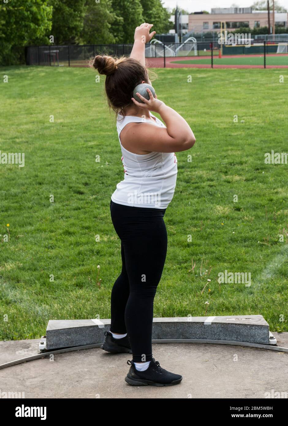 A high school girls is in the shot put circle getting ready to throw on