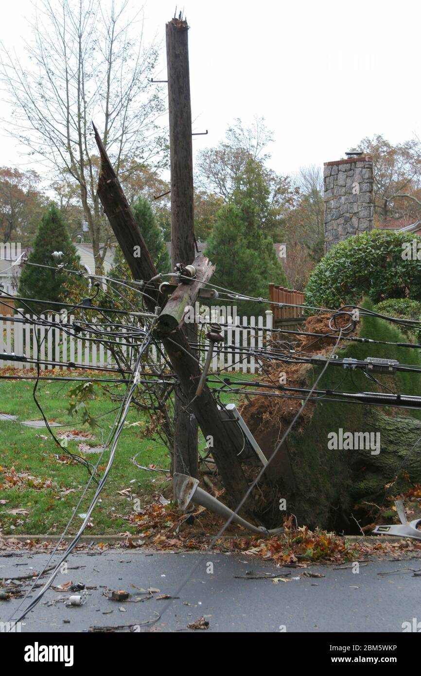 A telephone pole with electric wires breakes in half and falls during super storm sandy on long island Stock Photo