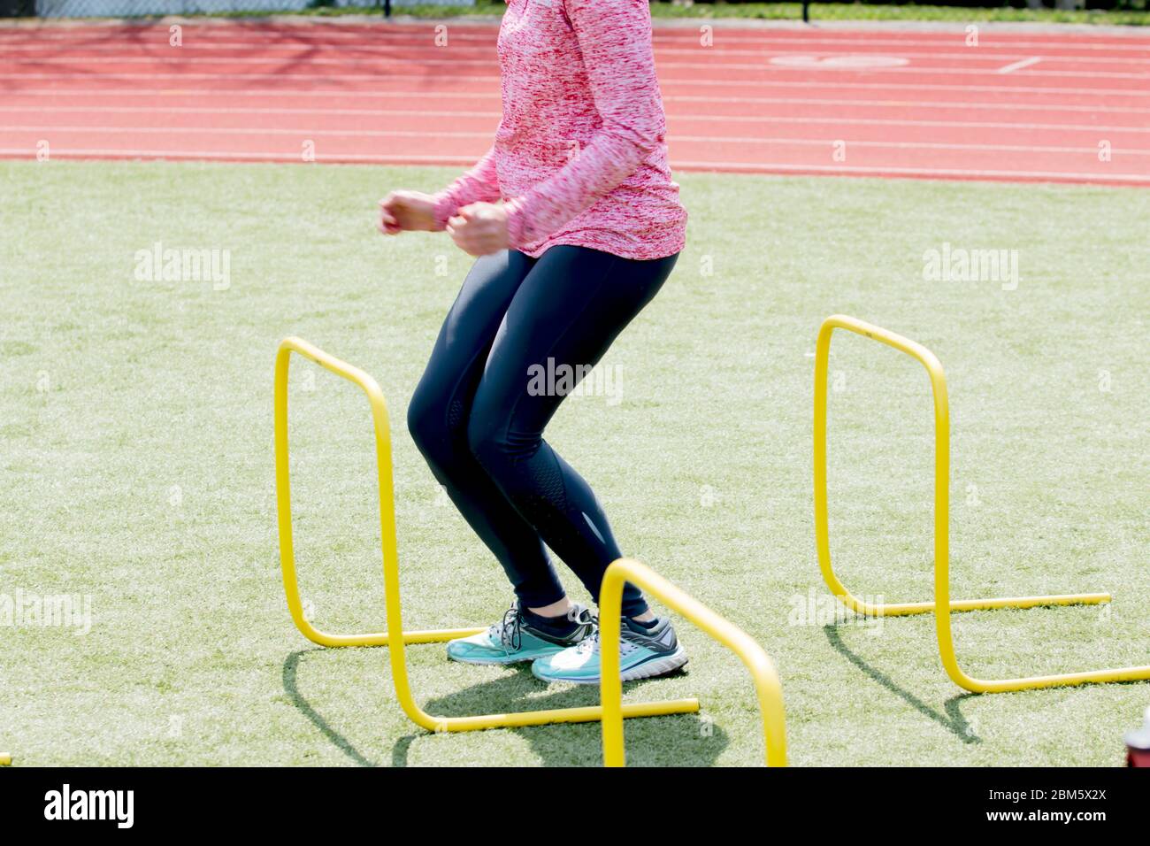 An athlete lands between yellow hurdles getting ready to jump over the