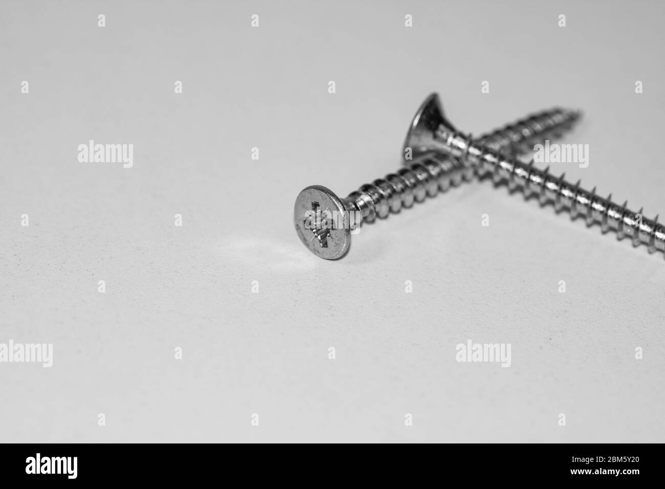 Close up photo of screws, set of screws in a construction abstraction. Industrial background with screws on a white board Stock Photo