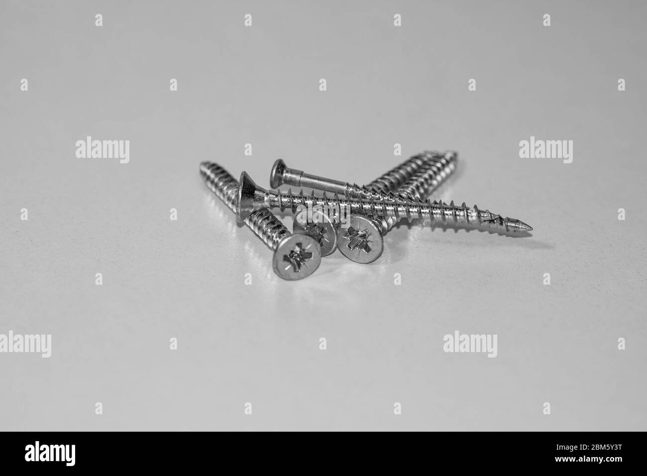 Close up photo of screws, set of screws in a construction abstraction. Industrial background with screws on a white board Stock Photo