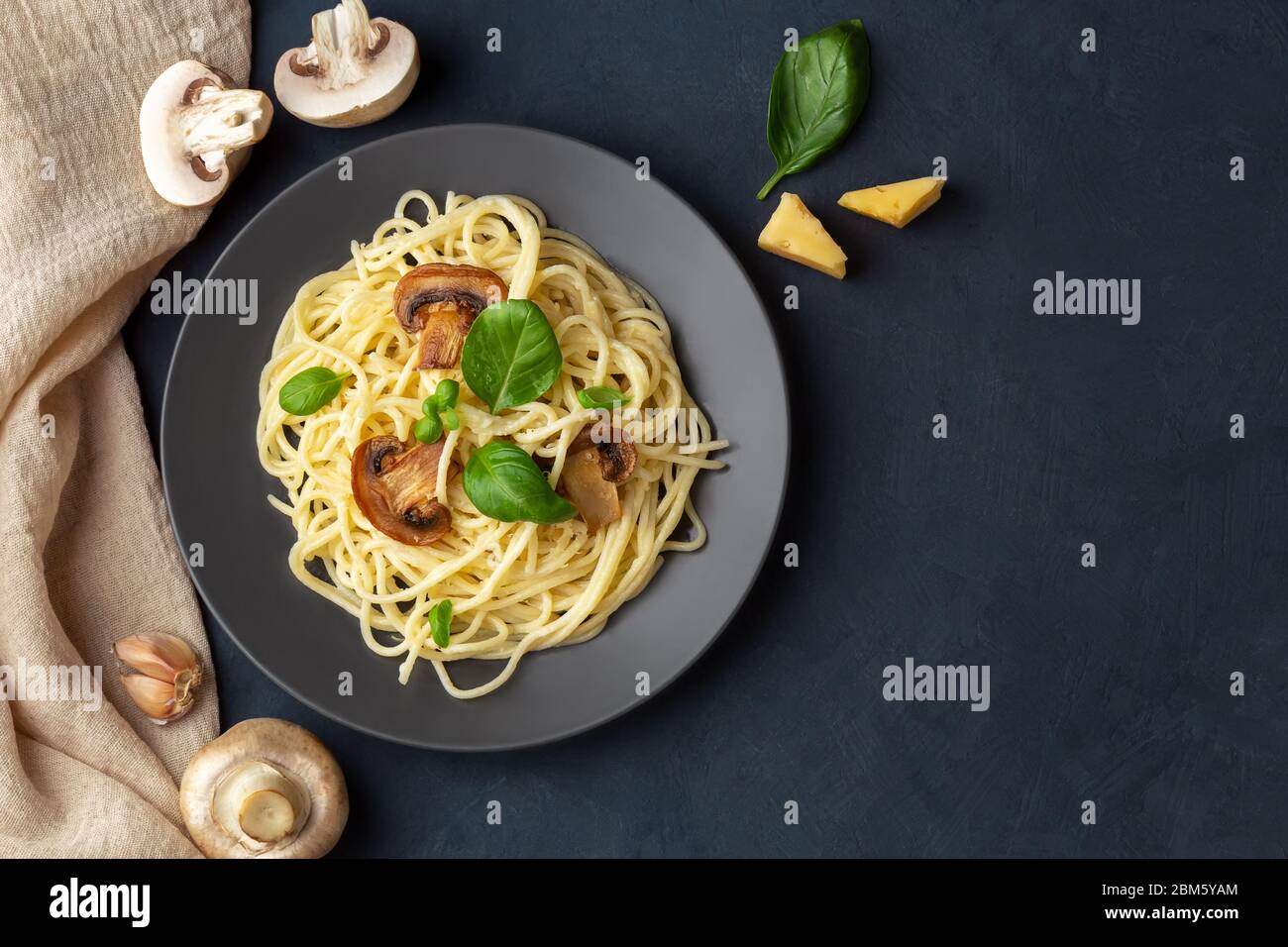 Mushroom pasta with cheese on a dark blue background. Top view, copy space. Stock Photo