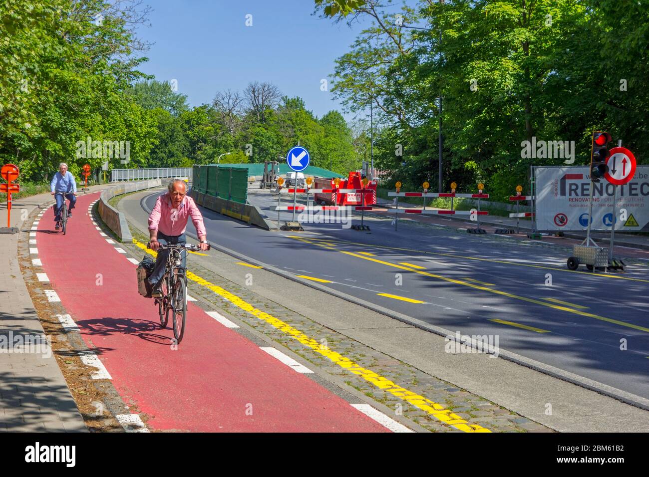 Cyclists riding on bicycle path past road works done at Mariakerkebrug, 60s bridge in the village Mariakerke near Ghent, East Flanders, Belgium Stock Photo