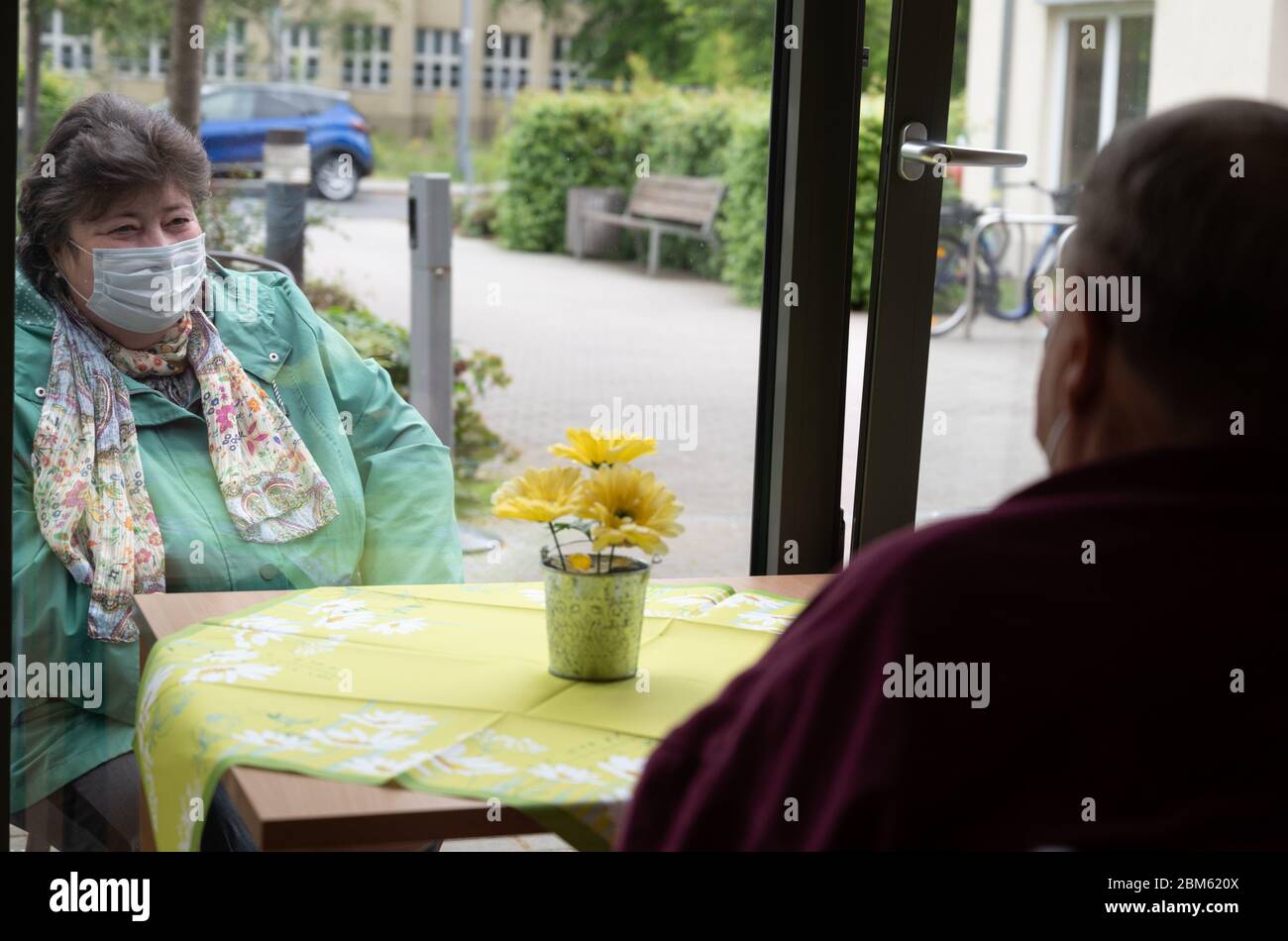 Berlin, Germany. 07th May, 2020. Ilona Spottke (l) and Karl Gegner are talking through a window pane on the ground floor of a nursing home. In the nursing home the residents can meet relatives. In the days of Corona, some nursing homes in Berlin have found visiting solutions that comply with the protection regulations. Credit: Christophe Gateau/dpa/Alamy Live News Stock Photo