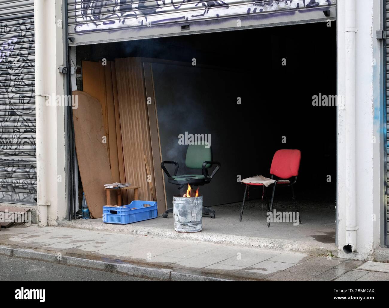 Burning trash can and two chairs in a garage in Nicosia, Cyprus Stock Photo
